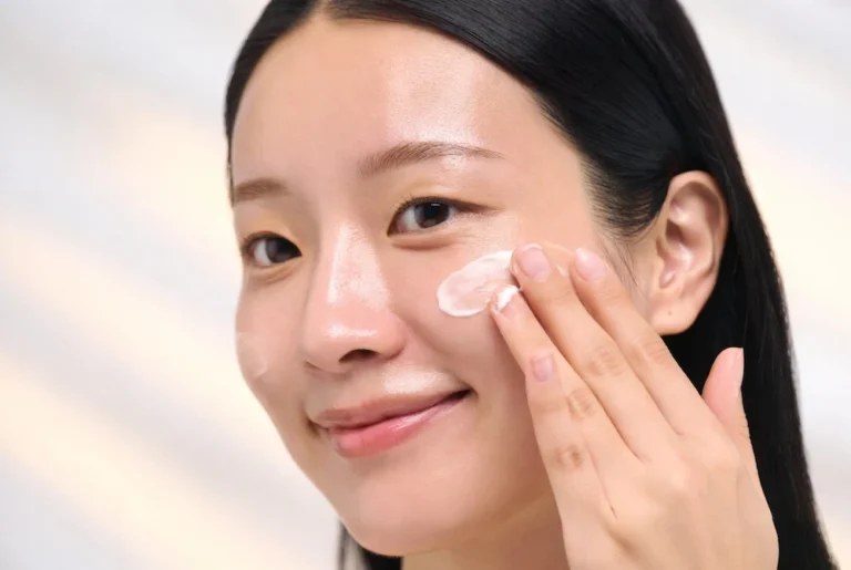 mujer asiática aplicando crema coreana hidratante sobre piel luminosa y saludable