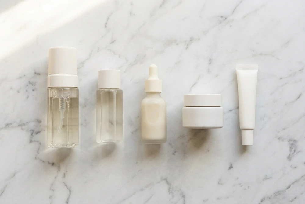 productos de skincare coreano ordenados por pasos sobre superficie de mármol blanco