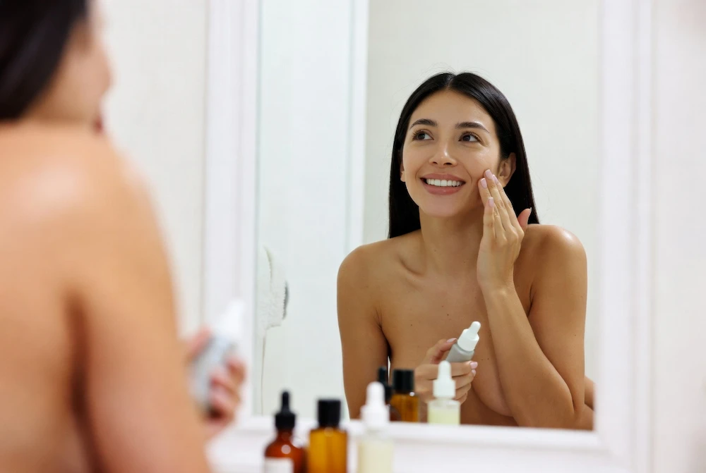 mujer joven aplicando su rutina de skincare frente al espejo