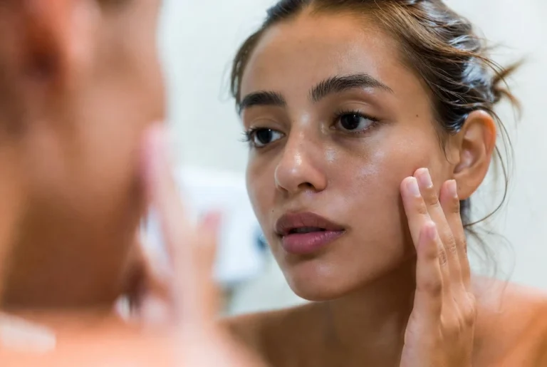 mujer con piel grasa revisando su rostro en espejo